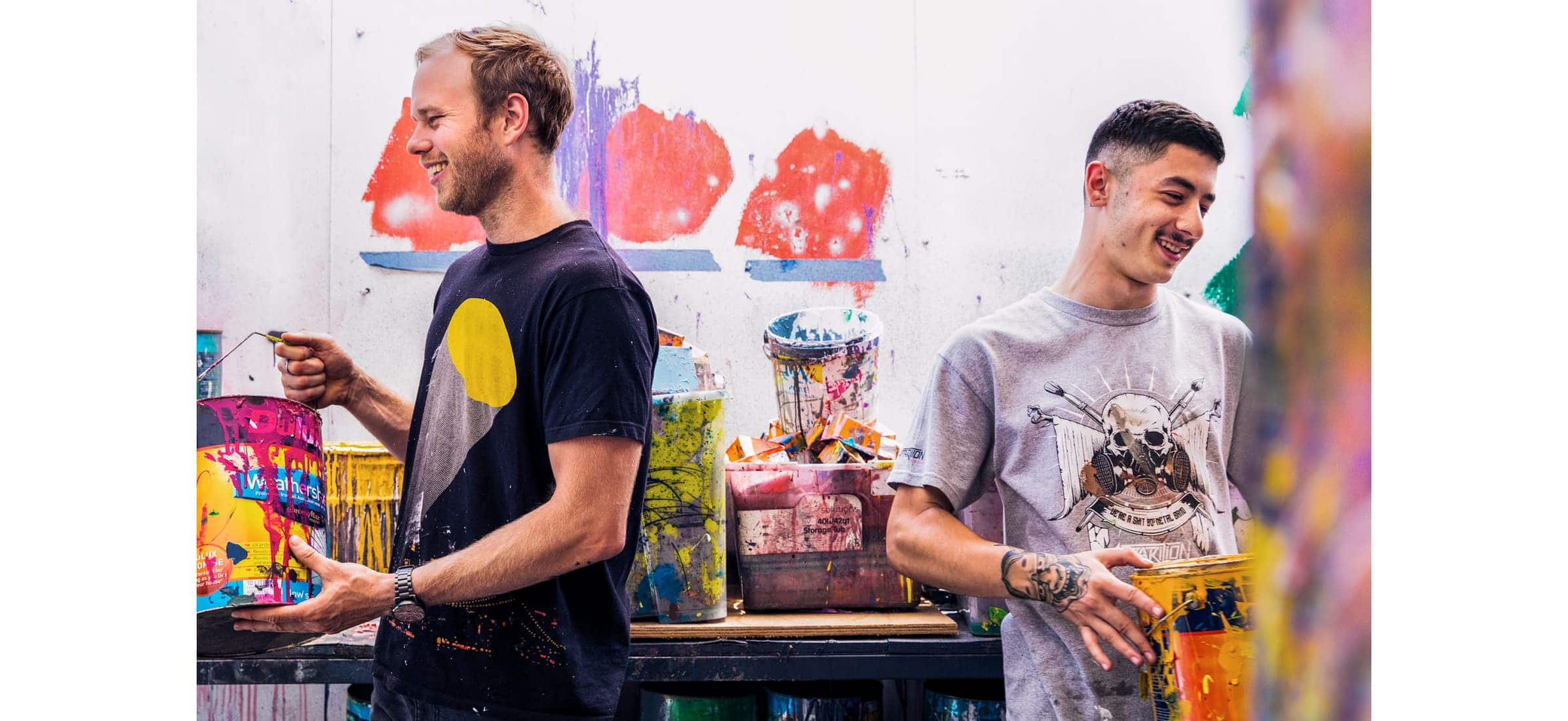 Tristan and a colleague holding paint cans in Apparition Media’s studio.